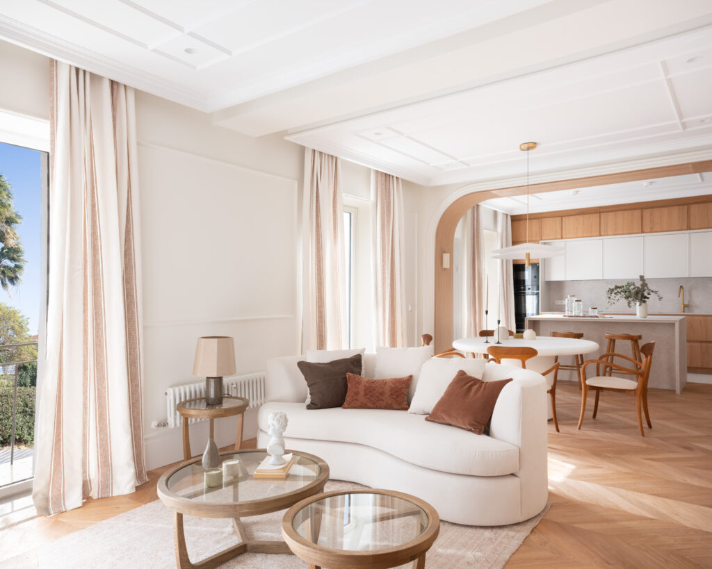 Salón en tonos neutros de vivienda reformada en Madrid, con sofá curvo y luz natural